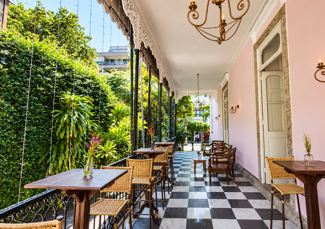 Terraço colonial com mesas de café e jardim